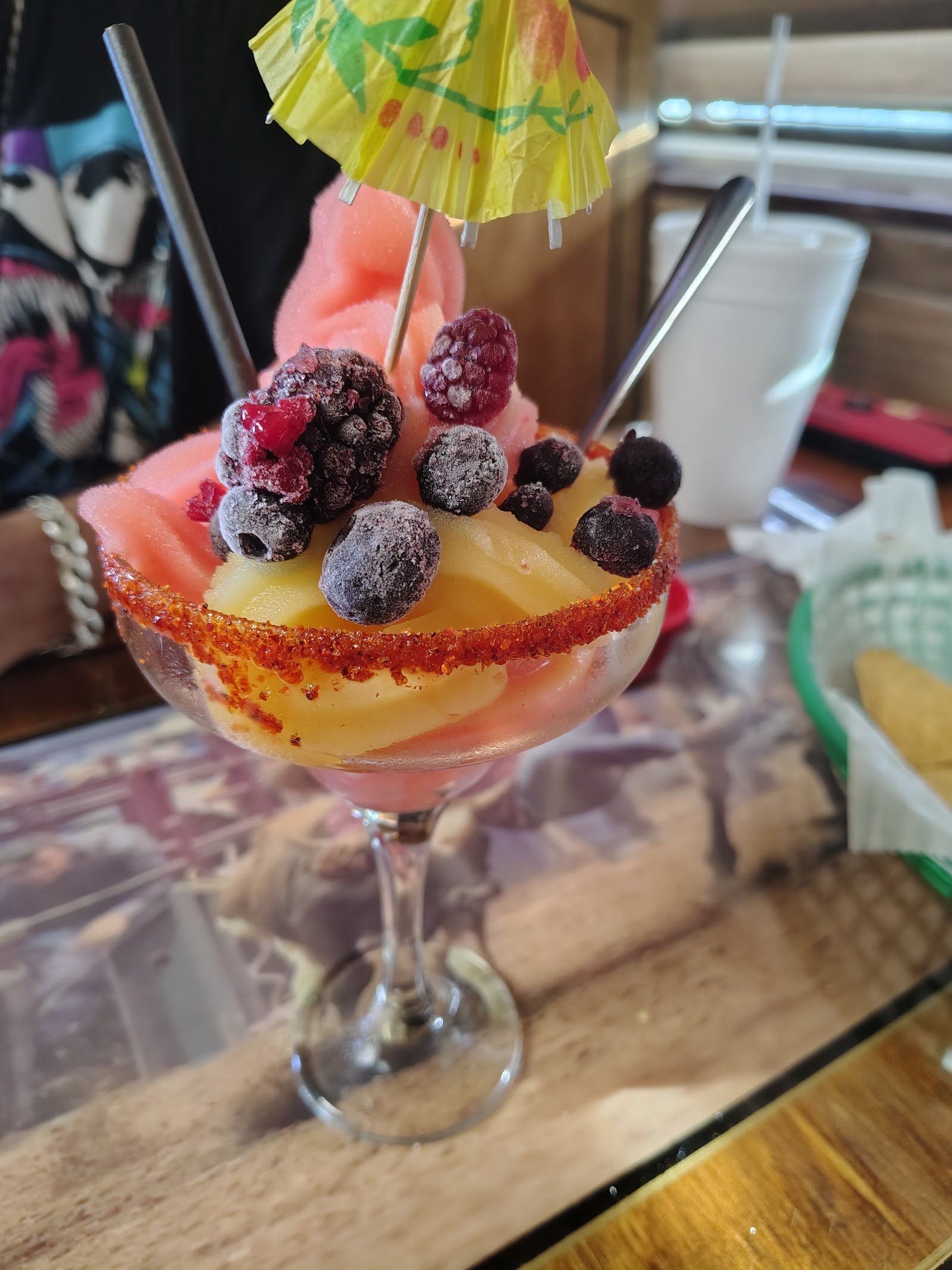 Fruit-topped frozen margarita with a cocktail umbrella