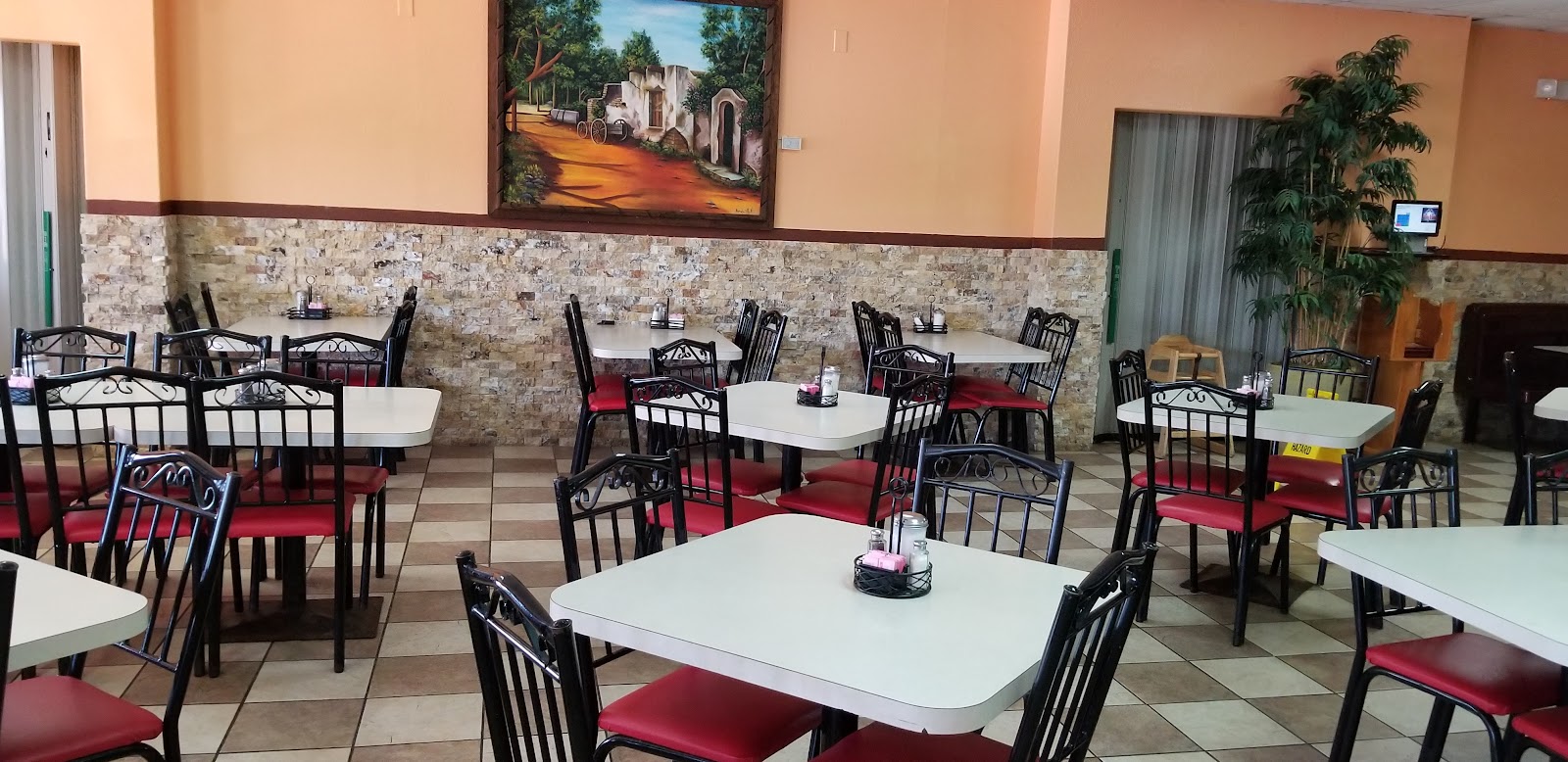Spacious dining room at La Parrilla 2 with warm stone walls and local artwork